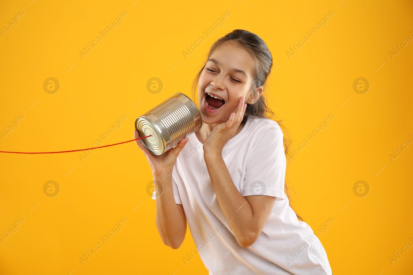 Photo of Girl using tin can telephone on yellow background