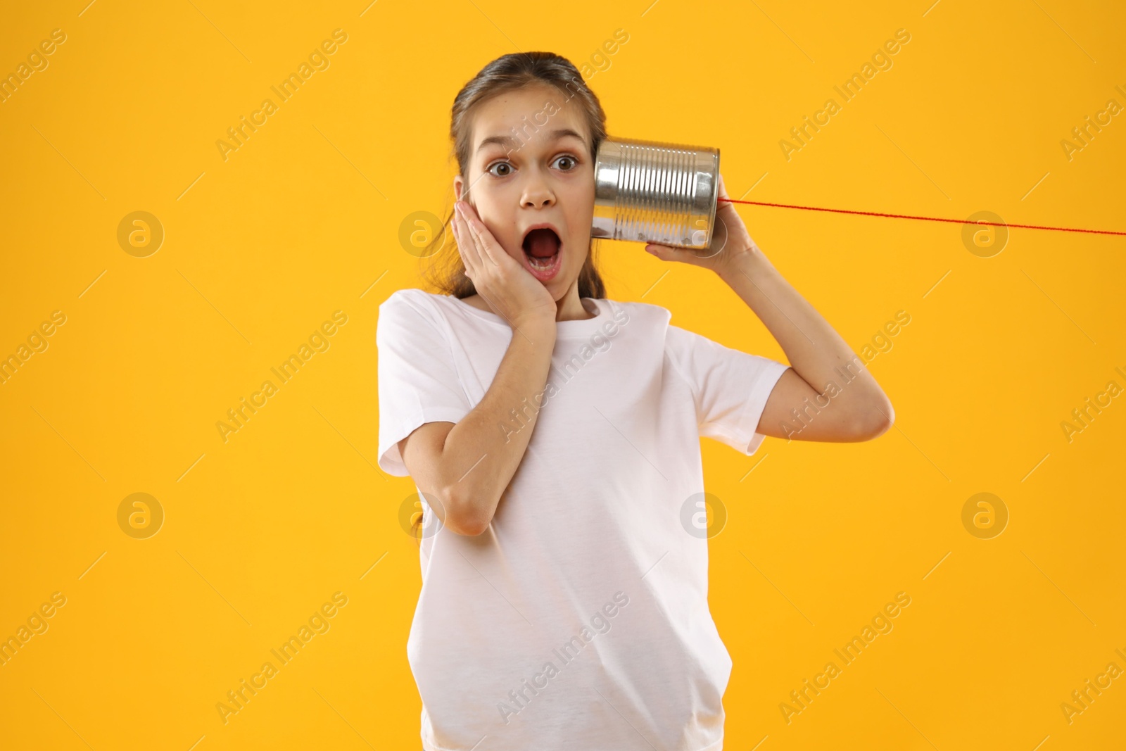 Photo of Girl using tin can telephone on yellow background