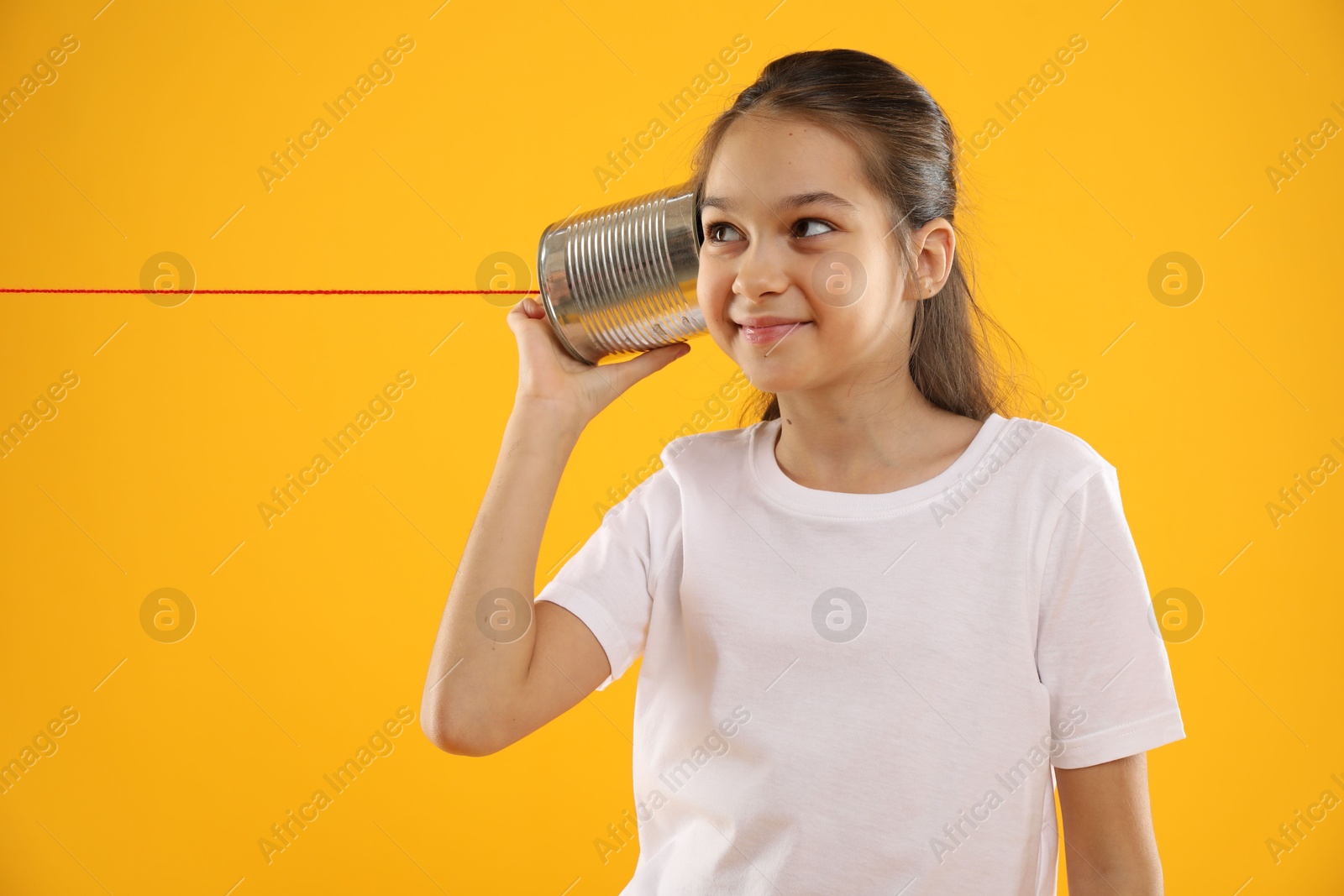 Photo of Girl using tin can telephone on yellow background