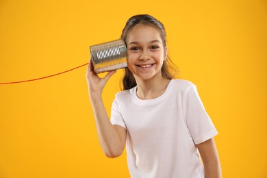 Photo of Girl using tin can telephone on yellow background