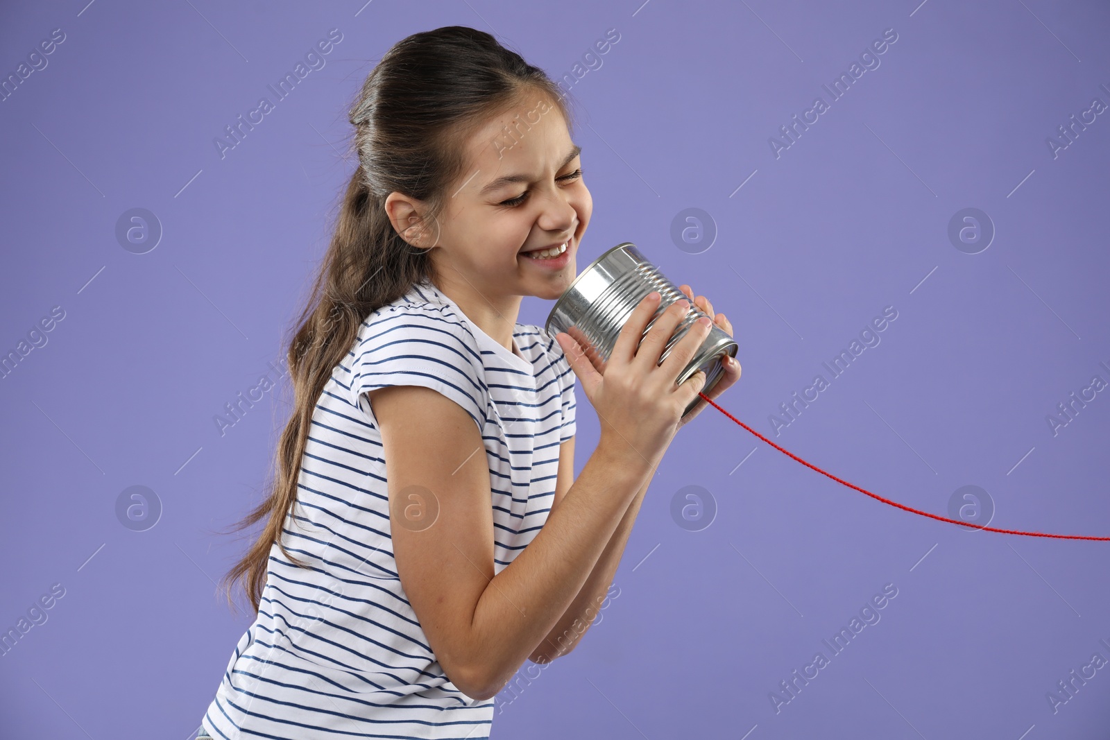 Photo of Girl using tin can telephone on violet background