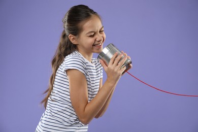 Photo of Girl using tin can telephone on violet background