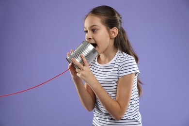 Photo of Girl using tin can telephone on violet background