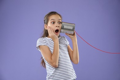 Photo of Girl using tin can telephone on violet background