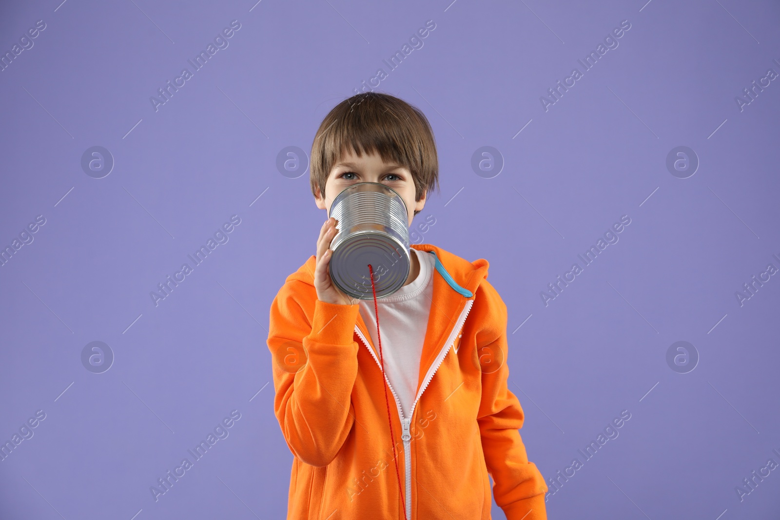 Photo of Boy using tin can telephone on violet background