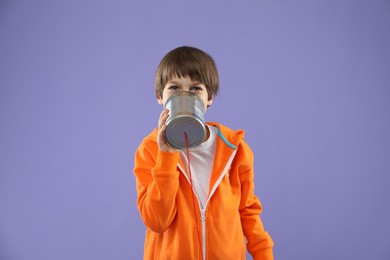 Photo of Boy using tin can telephone on violet background