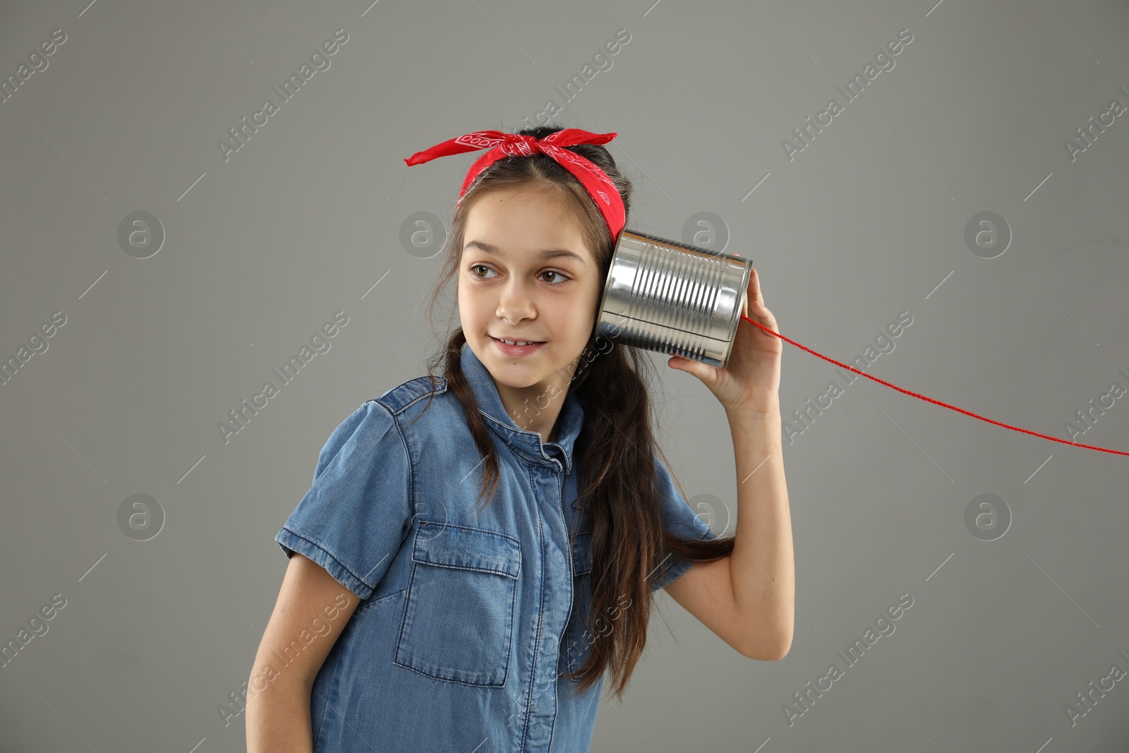 Photo of Girl using tin can telephone on gray background