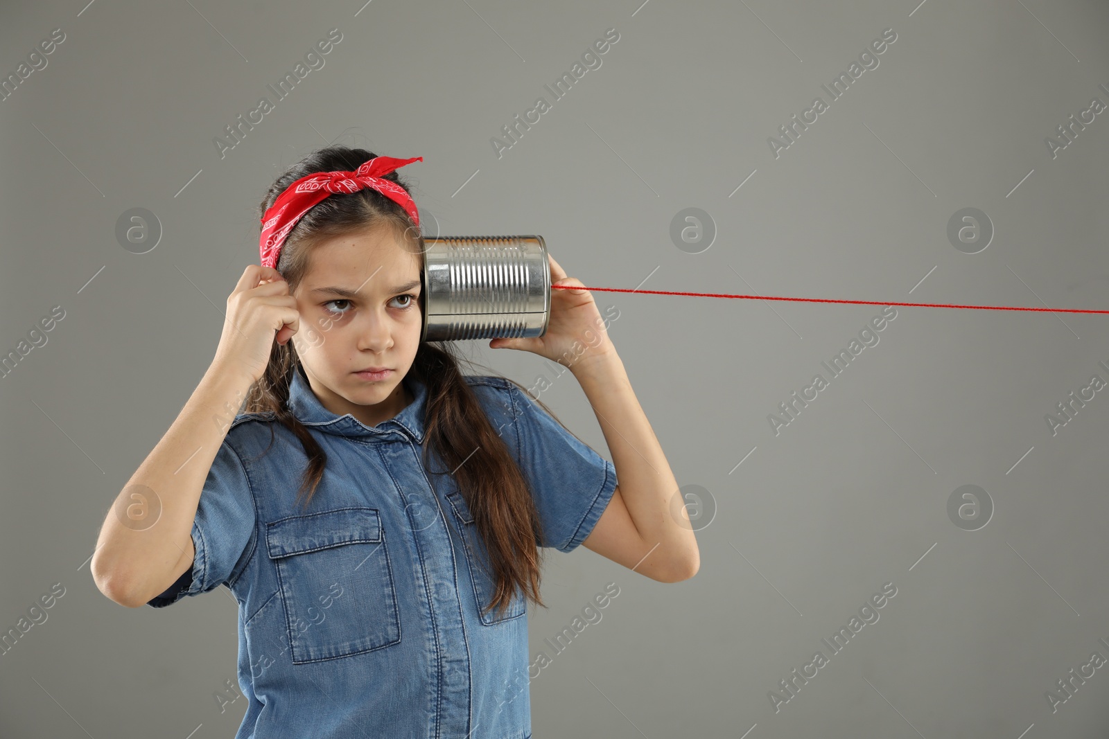 Photo of Girl using tin can telephone on gray background