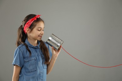 Photo of Girl using tin can telephone on gray background