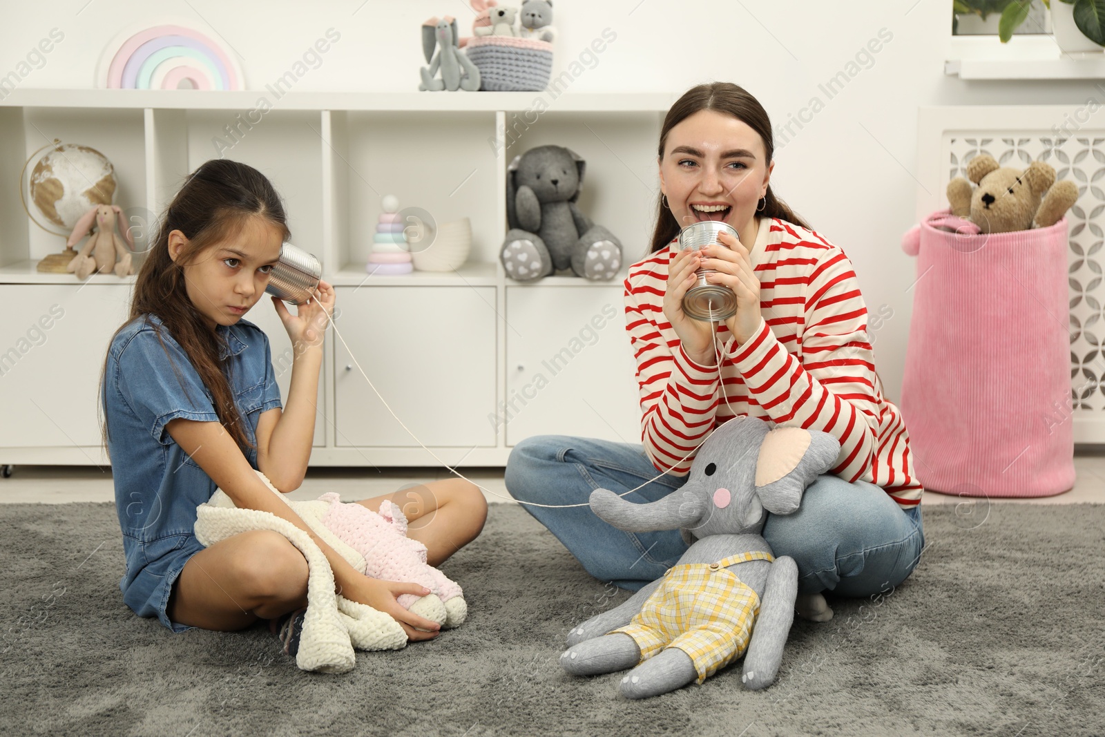 Photo of Woman and girl talking on tin can telephone indoors