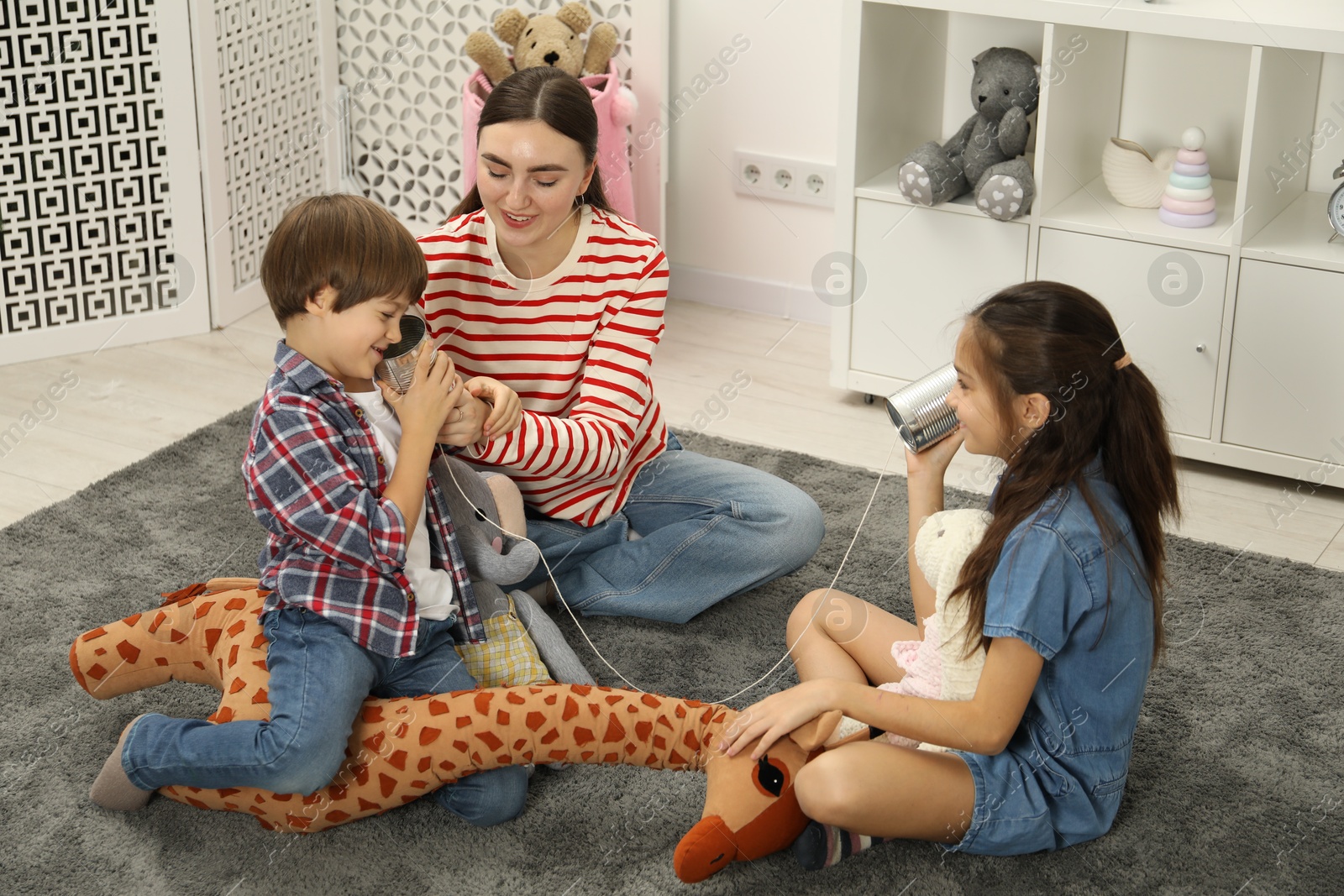 Photo of Woman and children talking on tin can telephone indoors