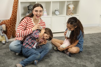 Photo of Woman and children talking on tin can telephone indoors