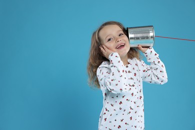 Photo of Girl using tin can telephone on blue background. Space for text