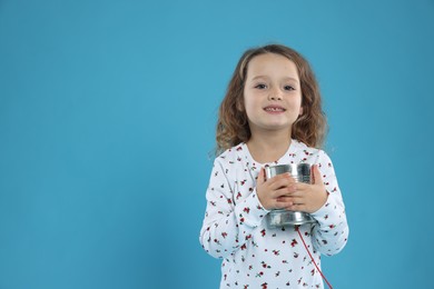 Photo of Girl using tin can telephone on blue background. Space for text