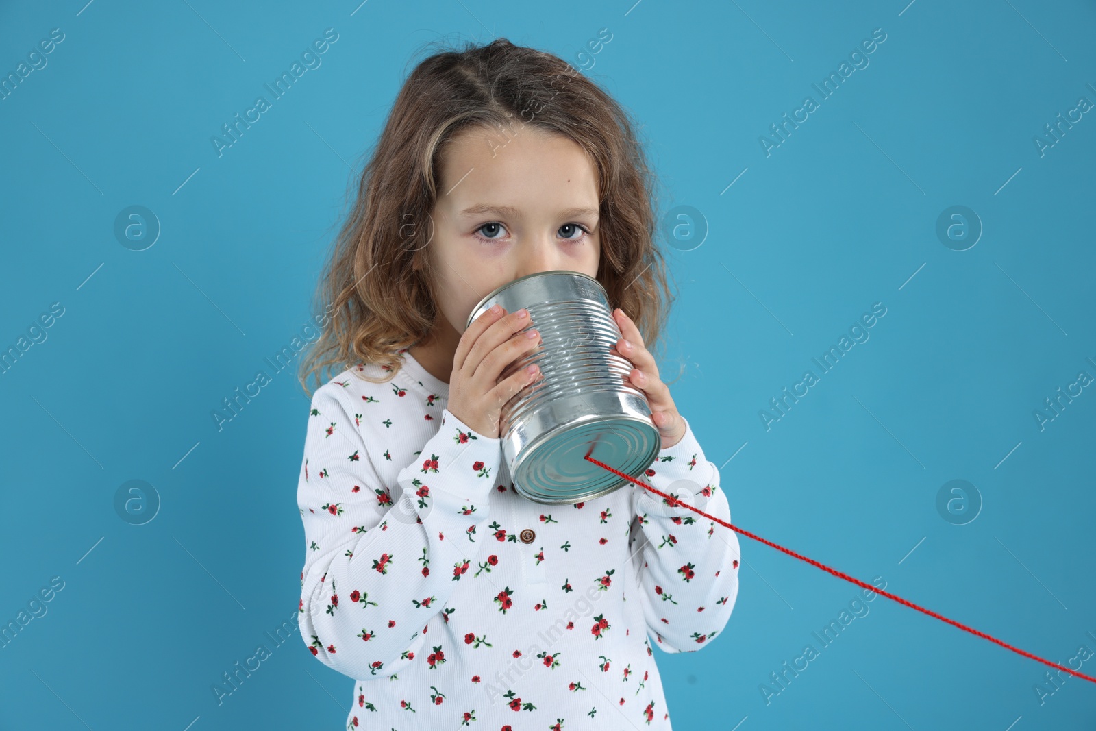 Photo of Girl using tin can telephone on blue background