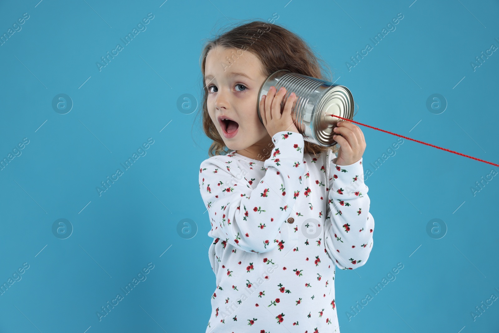 Photo of Girl using tin can telephone on blue background