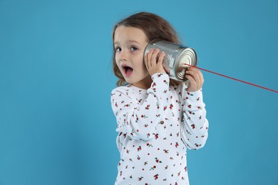 Photo of Girl using tin can telephone on blue background