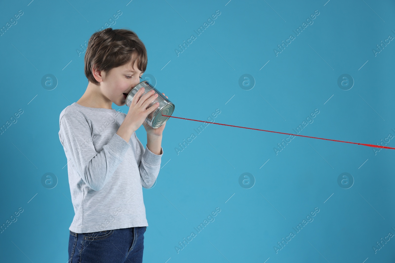 Photo of Boy using tin can telephone on blue background