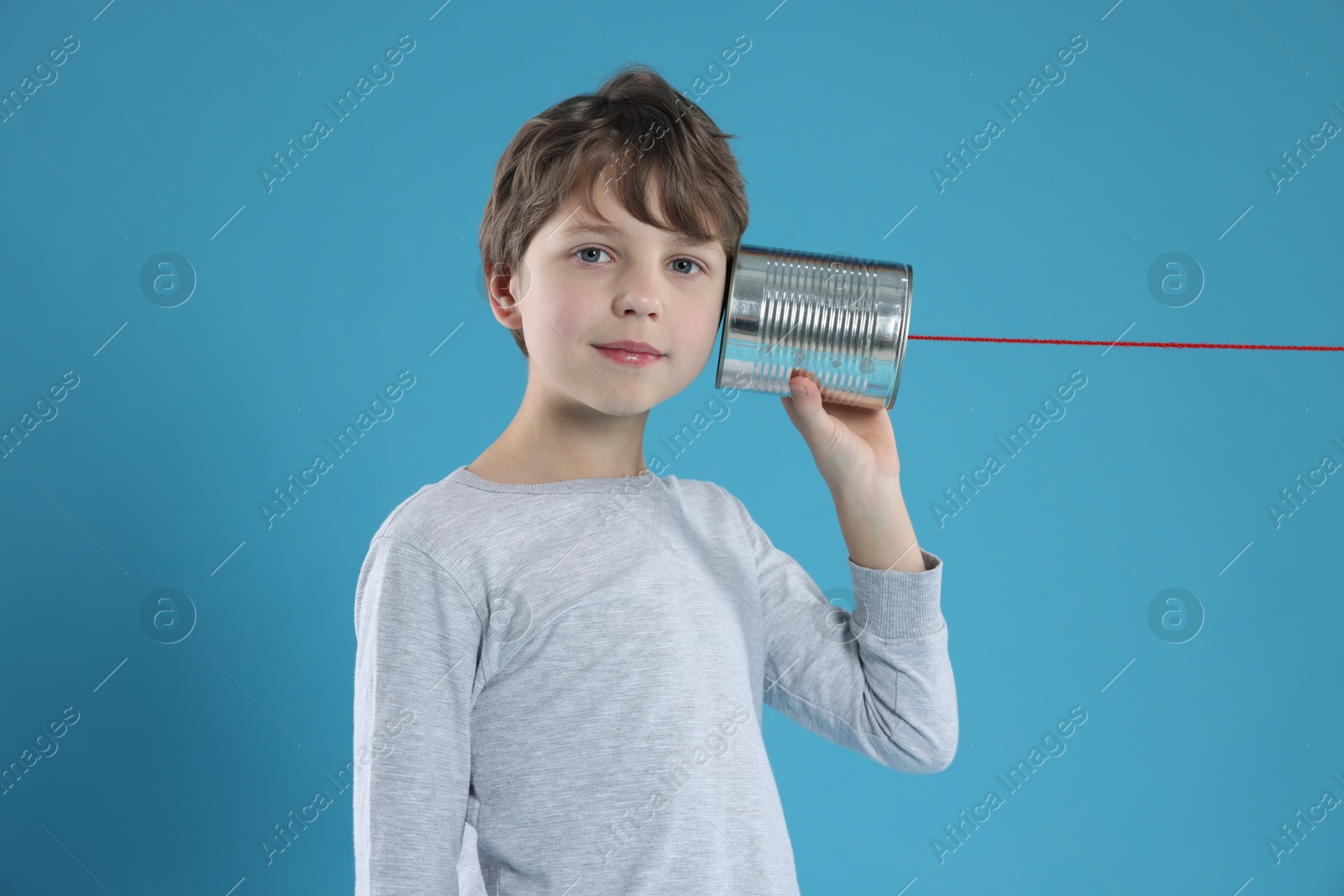 Photo of Boy using tin can telephone on blue background