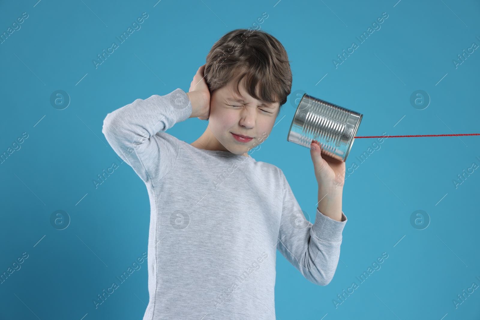 Photo of Boy using tin can telephone on blue background