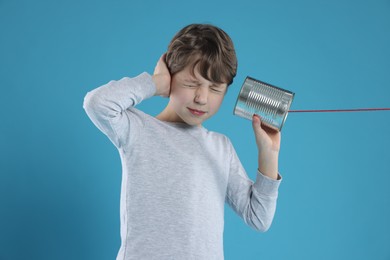 Photo of Boy using tin can telephone on blue background