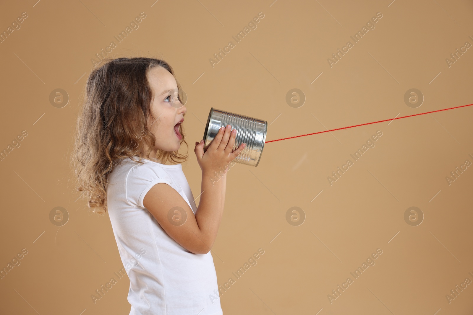 Photo of Girl using tin can telephone on beige background