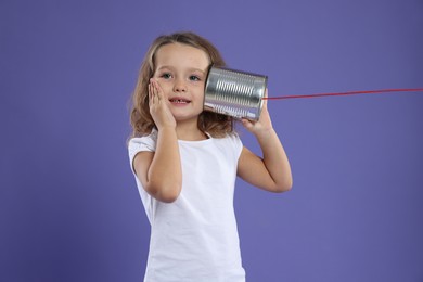 Photo of Girl using tin can telephone on violet background