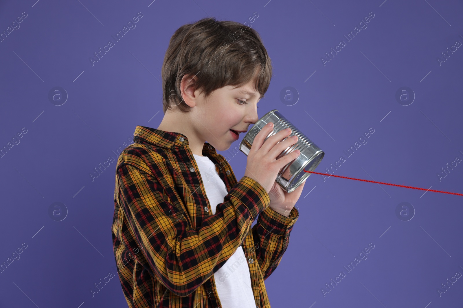 Photo of Boy using tin can telephone on violet background