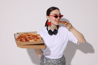 Photo of Woman in sunglasses eating pizza on white background