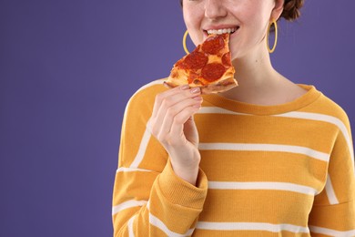 Photo of Woman eating pizza on violet background, closeup