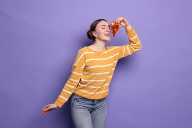 Photo of Beautiful woman with piece of delicious pizza on violet background