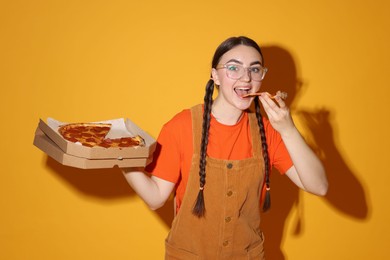 Photo of Beautiful woman with delicious pizza on orange background