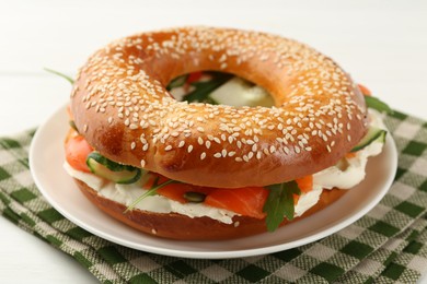 Photo of Delicious bagel with salmon, arugula and cream cheese on white wooden table, closeup