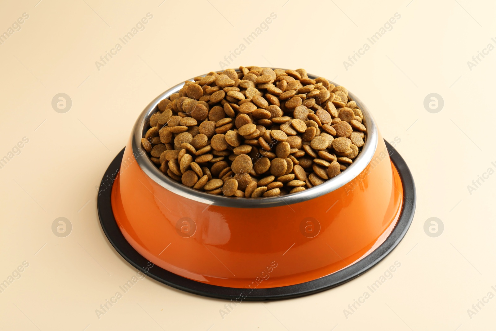 Photo of Dry pet food in feeding bowl on beige background