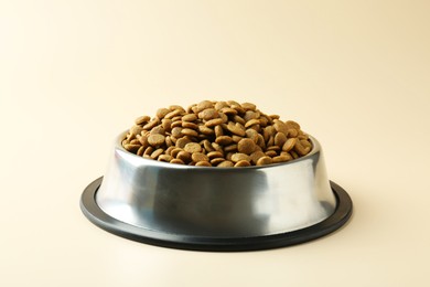 Dry pet food in feeding bowl on beige background