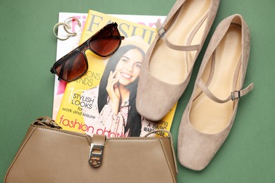 Photo of Pair of ballet flats, magazines and accessories on green background, flat lay