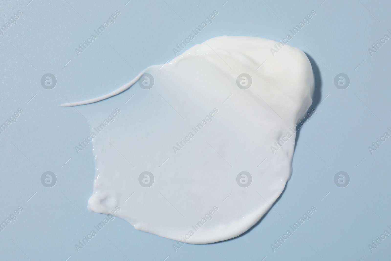 Photo of Sample of cream on light blue background, closeup. Cosmetic product