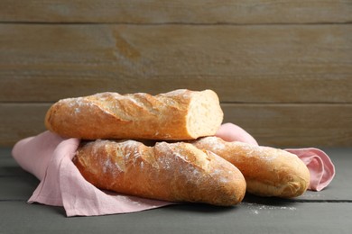 Photo of Cut fresh baguettes on grey wooden table