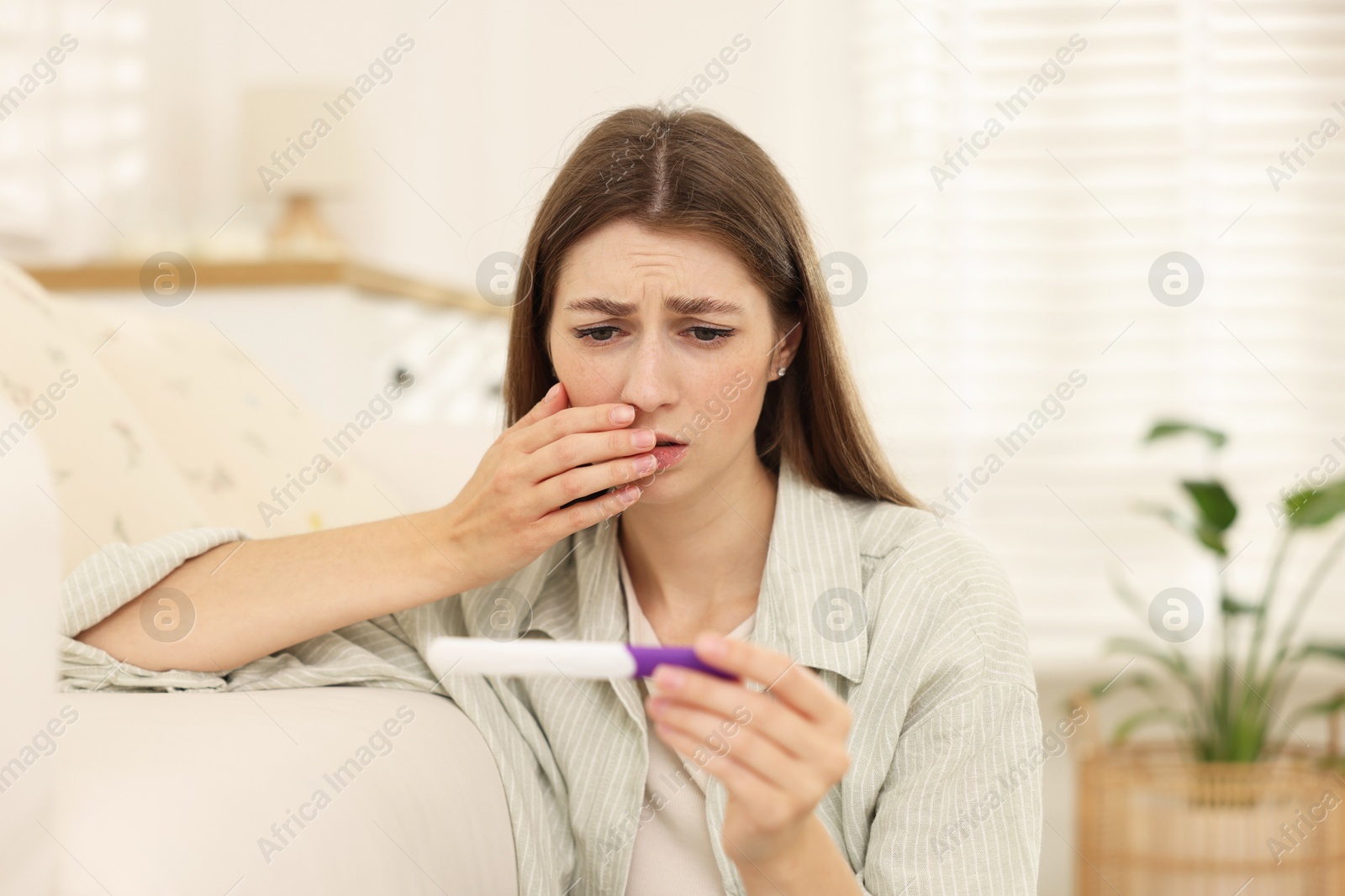 Photo of Upset woman with negative pregnancy test at home