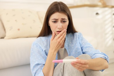 Photo of Upset woman with negative pregnancy test at home