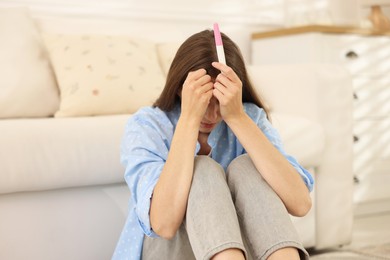 Photo of Upset woman with negative pregnancy test at home