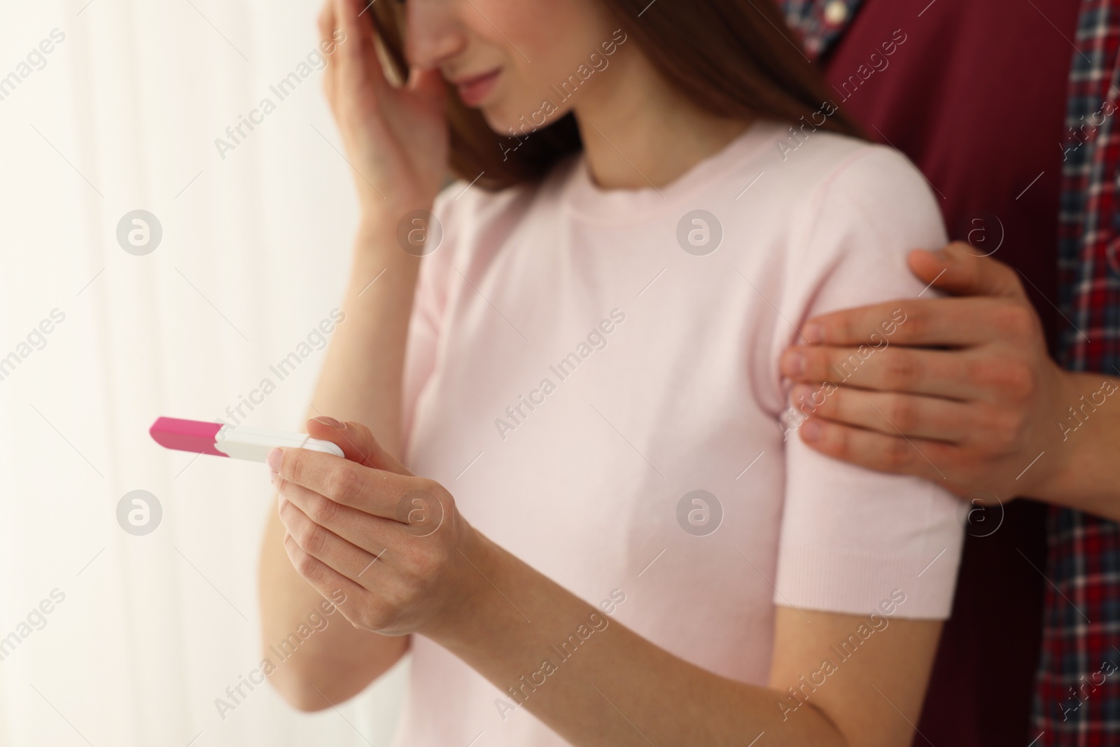 Photo of Woman with negative pregnancy test indoors, closeup. Man supporting his wife at home