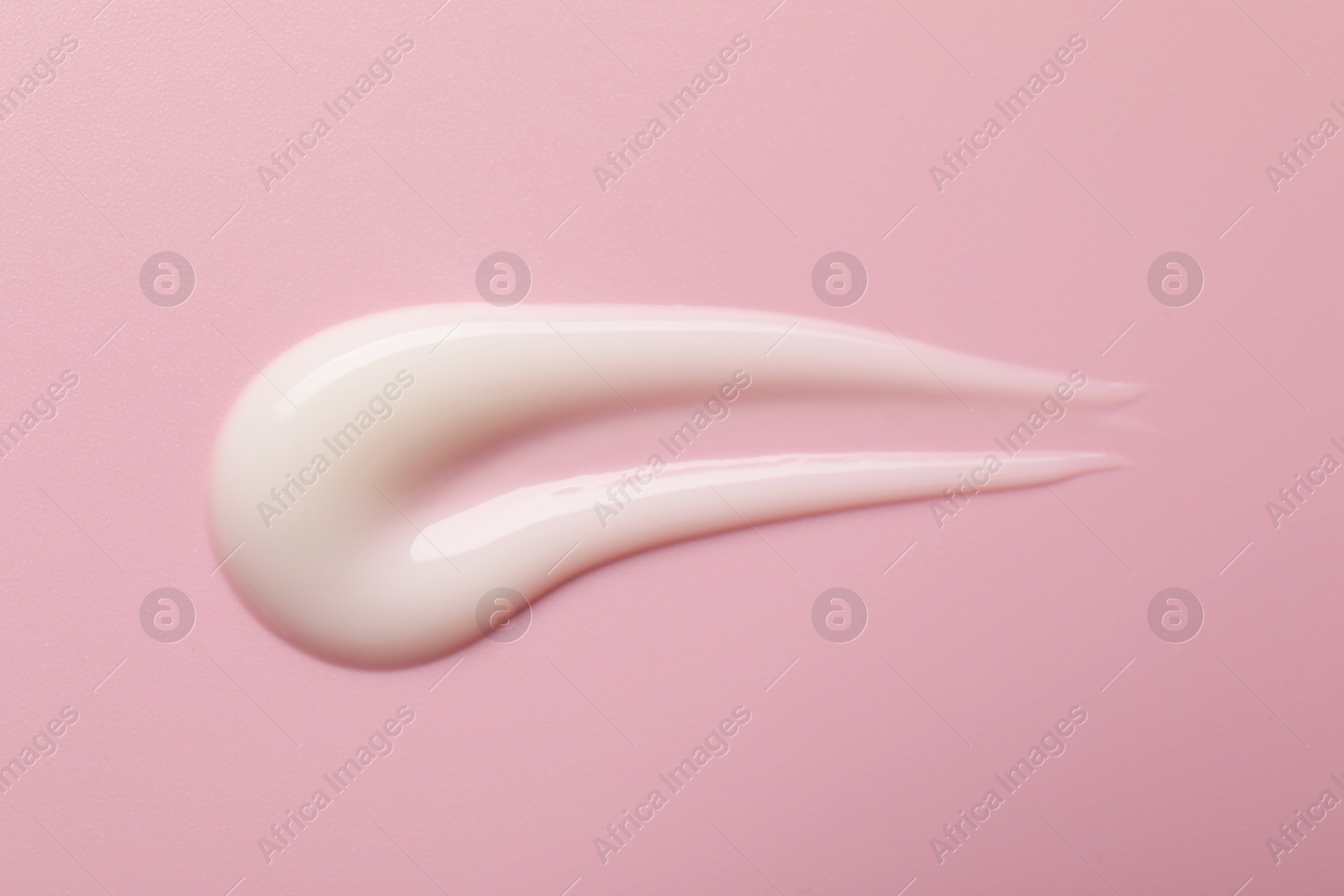 Photo of Cream on pink background, top view. Sample of cosmetic product