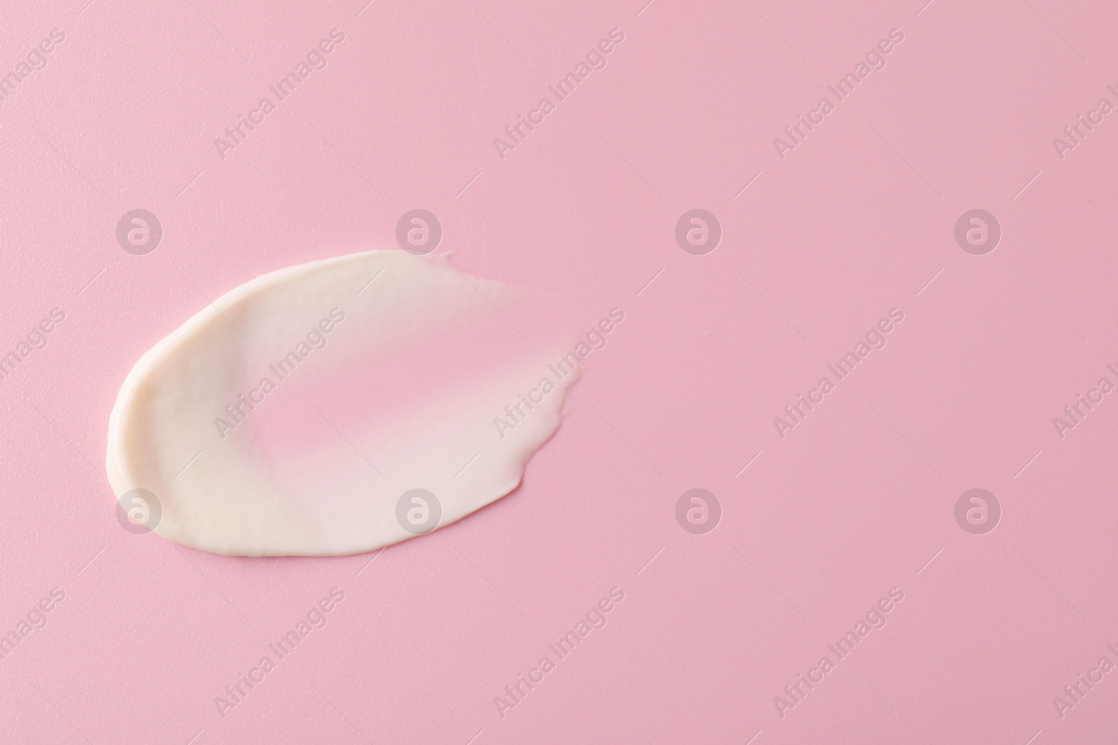 Photo of Cream on pink background, top view and space for text. Sample of cosmetic product