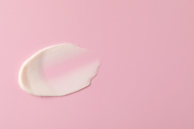 Photo of Cream on pink background, top view and space for text. Sample of cosmetic product