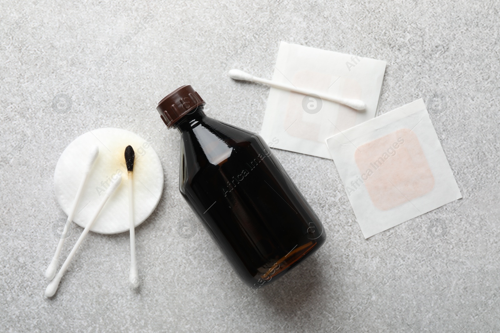 Photo of Topical iodine, cotton pad, swabs and adhesive bandages on light background, flat lay