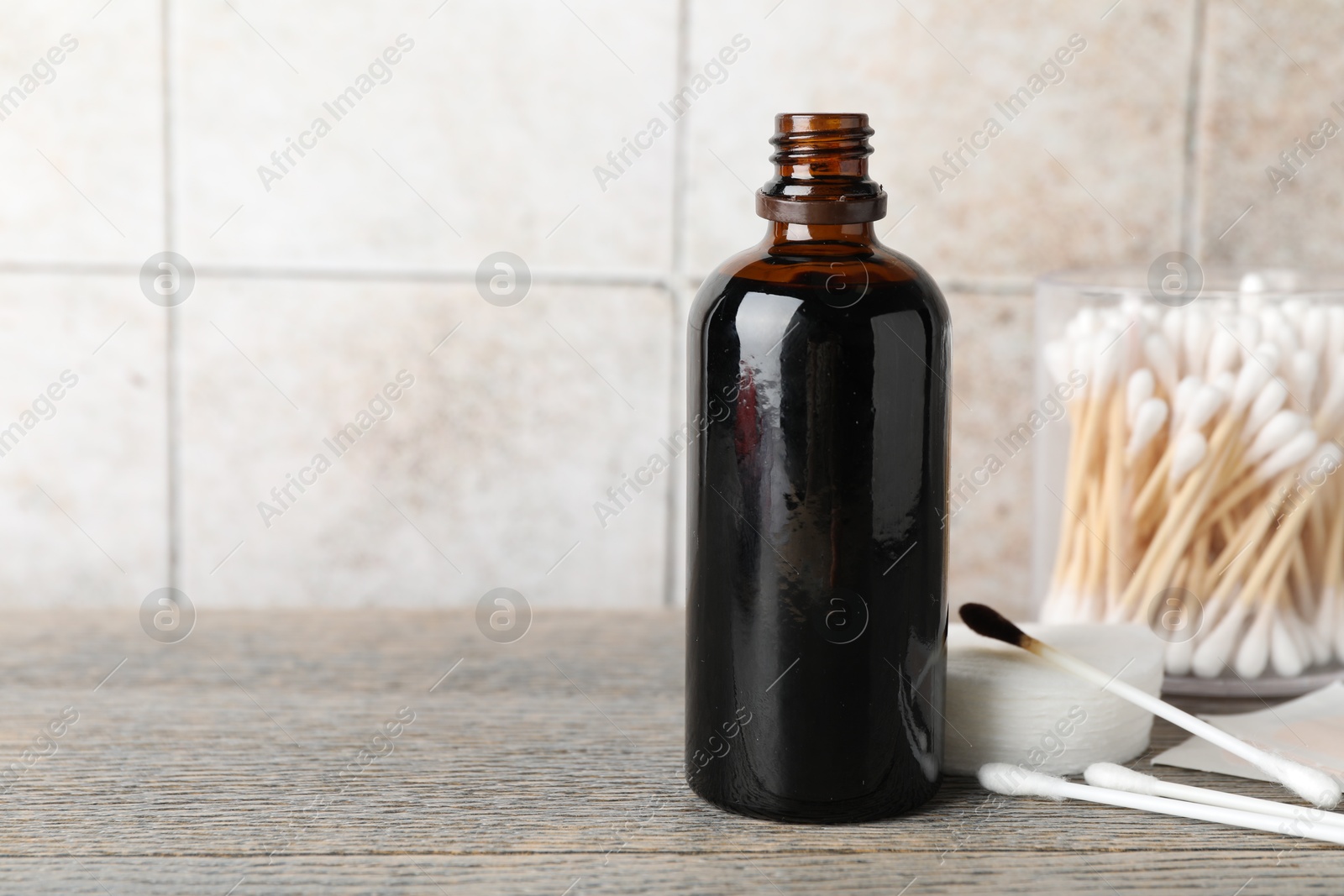 Photo of Topical iodine, cotton pads, swabs and adhesive bandages on wooden table. Space for text