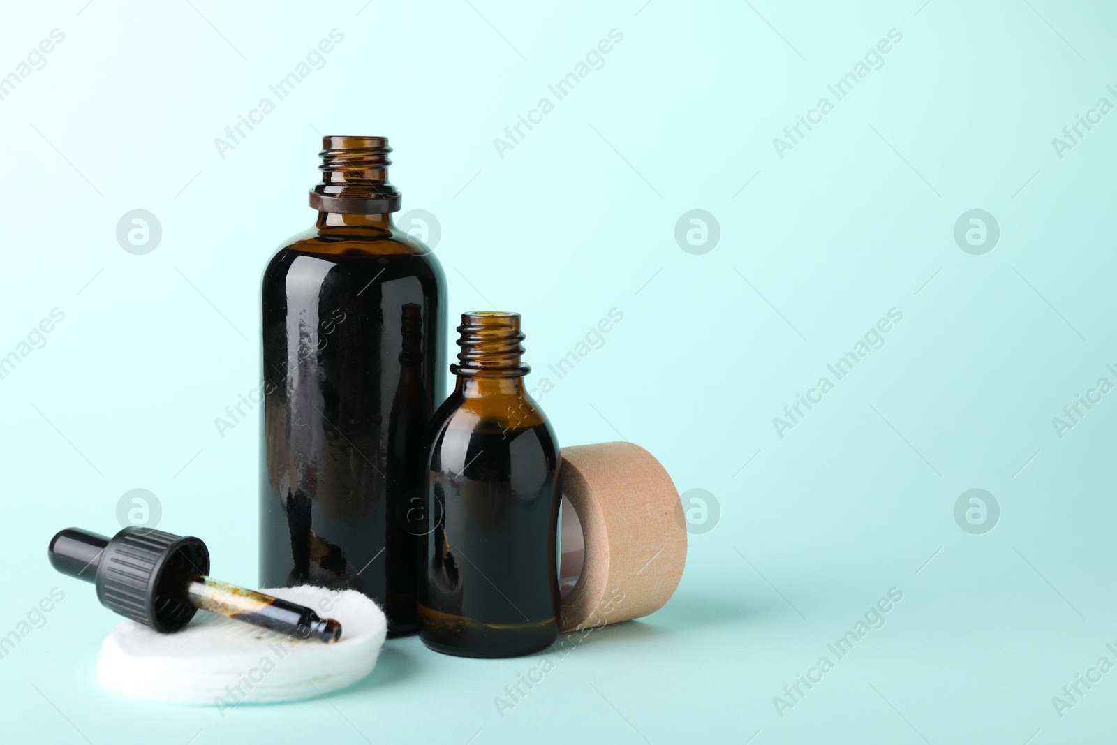 Photo of Topical iodine, cotton pads and adhesive bandage on light blue background. Space for text