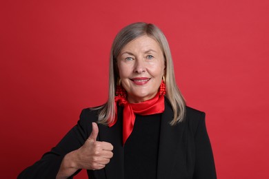 Photo of Senior woman showing thumbs up on red background