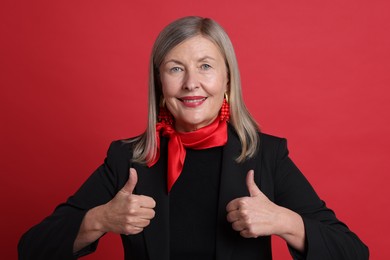 Photo of Senior woman showing thumbs up on red background